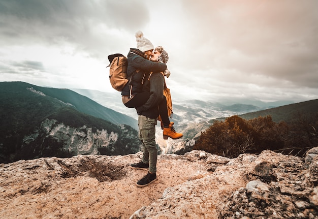 Photo couple de randonneurs amoureux ont un baiser romantique au sommet d'une montagne en hiver. les jeunes s'embrassent dans la nature.
