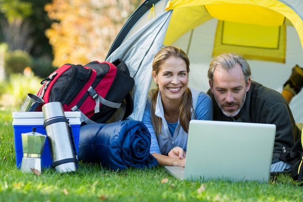 Couple de randonneurs heureux à l'aide d'un ordinateur portable