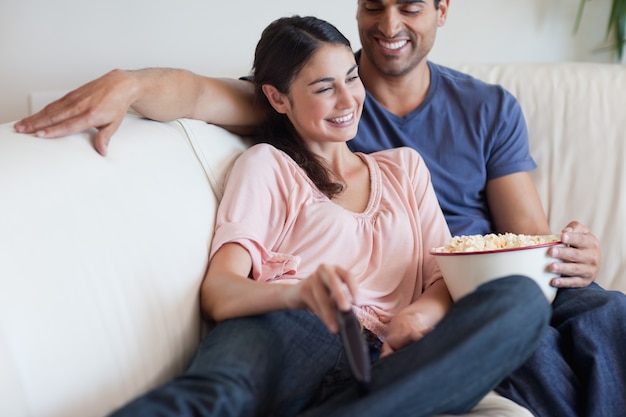 Couple ravi de regarder la télévision tout en mangeant du maïs soufflé