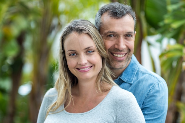 Couple regardant la caméra et souriant à l&#39;extérieur