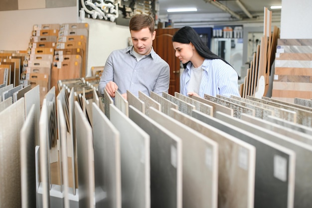 Couple regardant de la céramique et des carreaux pour leur nouveau sol. Ils choisissent dans un magasin de meubles