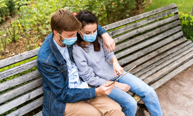 Couple regardant une tablette tout en portant des masques médicaux