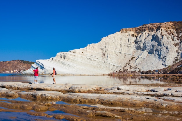 Un couple regarde et admire la Scala dei Turchi. Une fascinante roche calcaire escarpée sur une mer incroyable à Realmonte, Agrigente. Sicile