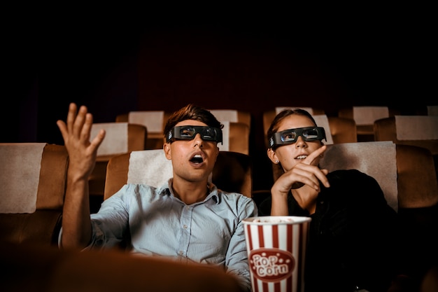 Couple regarde un film en 3D dans le théâtre avec pop-corn sourire et visage heureux