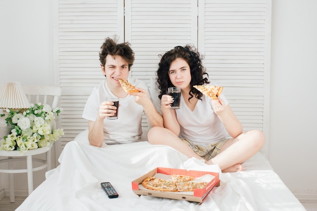 Couple, regarder télé, dans lit, et, pizza mangeant