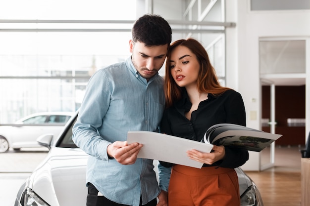 Couple, regarder, voiture, concessionnaire, journal