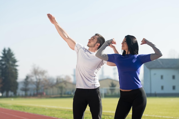 Couple de remise en forme debout fort dans la zone du parc de la ville et flexion des muscles modèle de bodybuilder athlétique musclé posant après les exercices