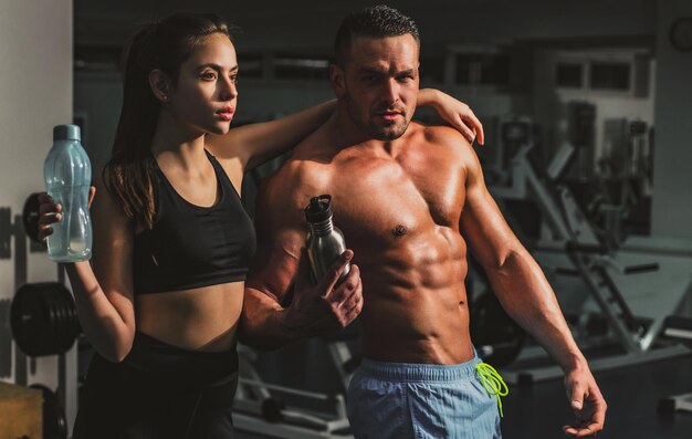 Couple de remise en forme à la salle de sport entraîneur personnel aide-soignant travaillant rester hydraté sportif concept sport