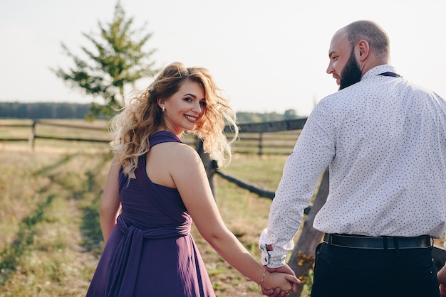 Couple à un rendez-vous. Robe violette. Mariée et marié. Marcher sur le terrain. Histoire d'amour.