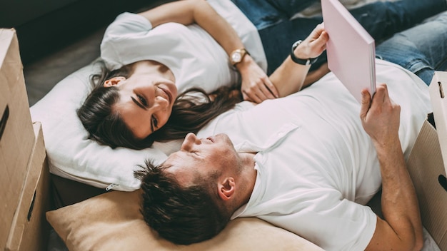 Couple reposant sur le sol le jour de l'emménagement dans un nouvel appartement