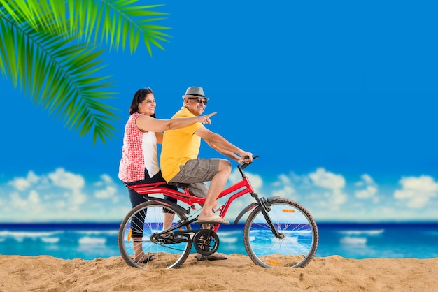 Couple de retraités asiatiques indiens avec leur vélo ou leur vélo sur la plage, effet de mauvaise humeur