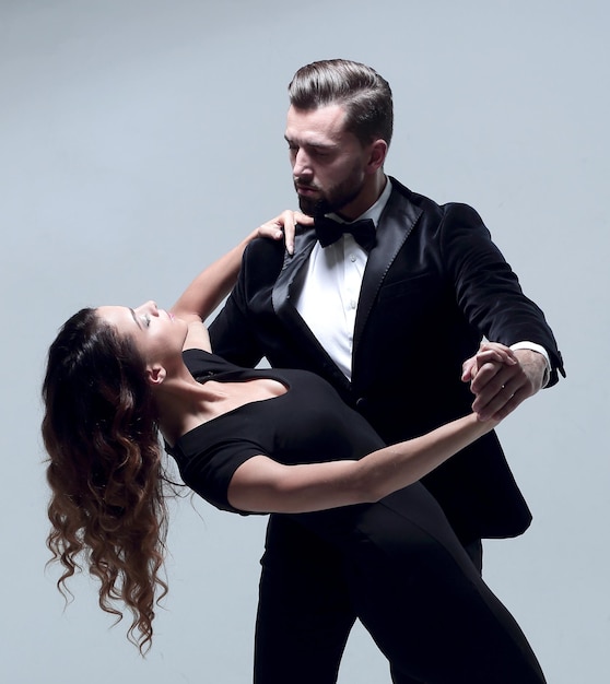 Couple rétro bien habillé dansant le tango sur fond de studio gris