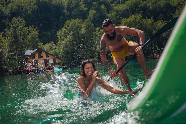 Couple riant en tombant du paddle board