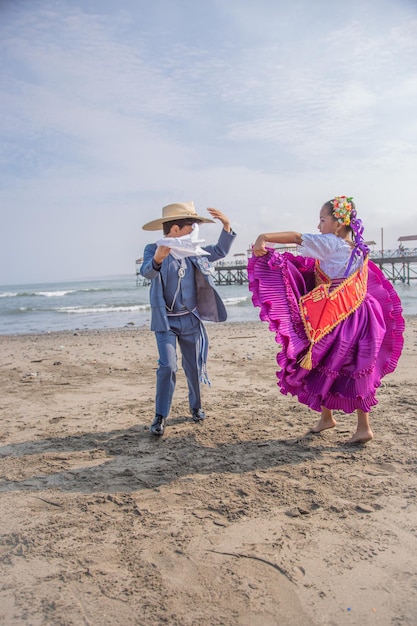 un couple en robe traditionnelle dansant sur la plage