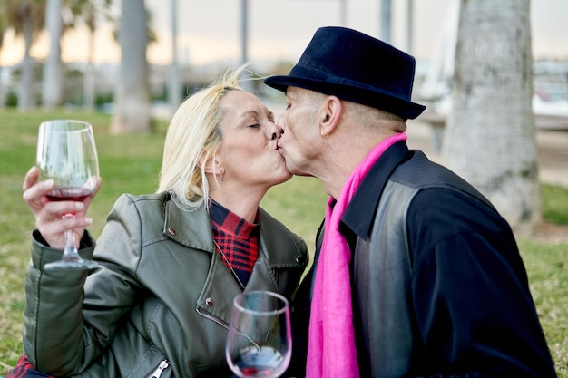 Couple romantique d'âge moyen montrant de l'affection avec une boisson au vin