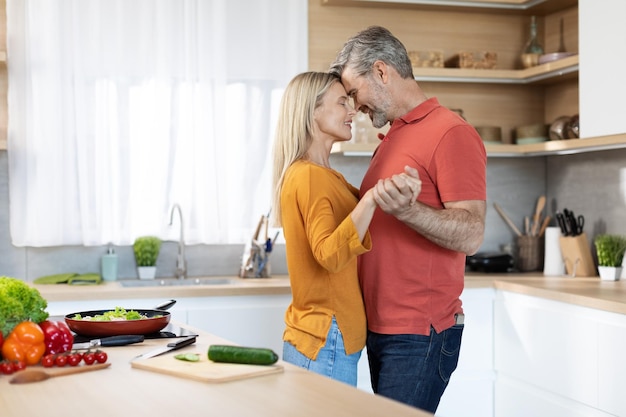 Couple romantique d'âge moyen s'amusant à danser dans la cuisine