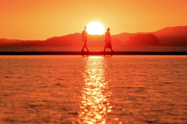 Couple romantique amoureux assis ensemble sur une balançoire à corde au coucher du soleil silhouettes de jeune homme et femme en vacances ou en lune de miel