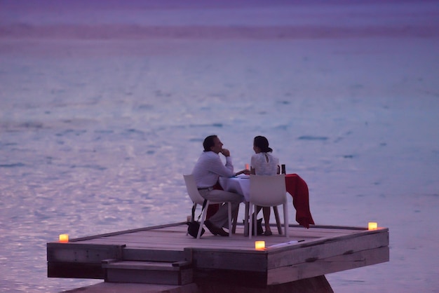 couple romantique amoureux dîner dans un restaurant en plein air avec des bougies avec la mer en arrière-plan