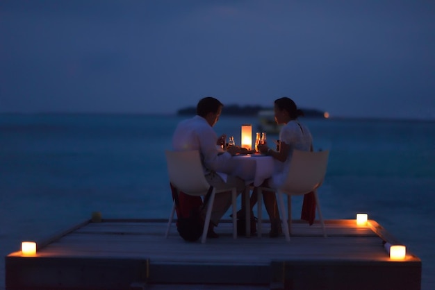 couple romantique amoureux dîner dans un restaurant en plein air avec des bougies avec la mer en arrière-plan