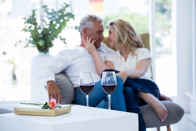 Photo couple romantique assis sur un fauteuil avec du vin et une boîte-cadeau