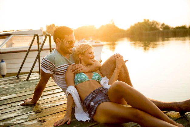 Couple romantique assis sur la jetée en bois sur le lac