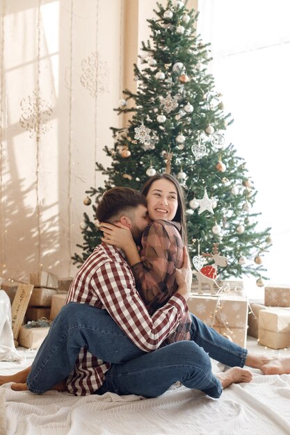 Couple romantique assis près de l'arbre de Noël et étreignant