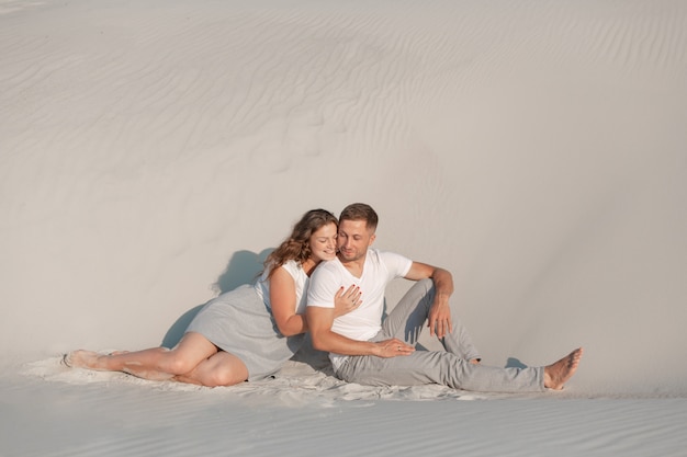 Couple romantique assis sur le sable blanc et huggins, dans le désert