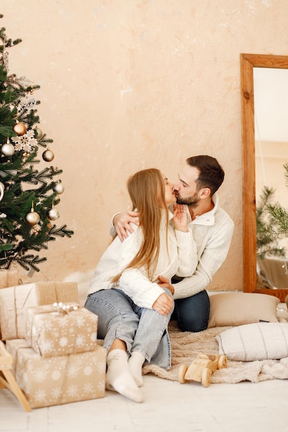 Couple romantique assis sur un sol près de l'arbre de Noël à la maison