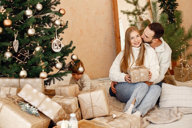 Couple romantique assis sur un sol près de l'arbre de Noël à la maison