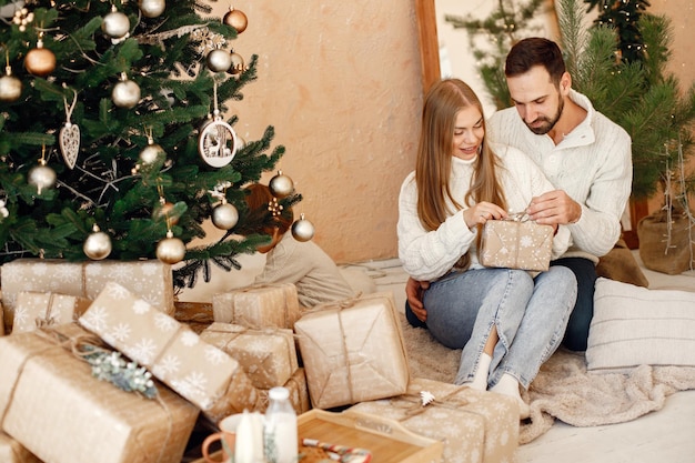 Couple romantique assis sur un sol près de l'arbre de Noël à la maison