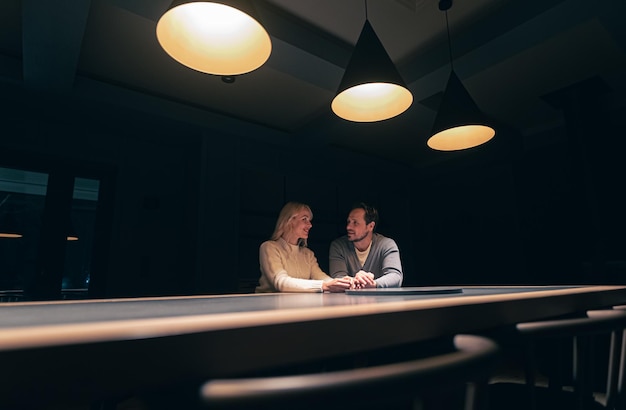 Le couple romantique assis à la table dans un restaurant de nuit vide