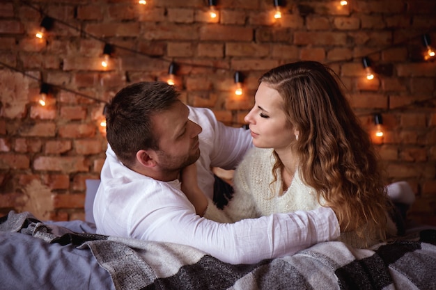 Couple romantique au lit contre un mur de briques