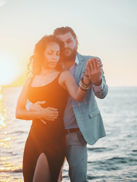 Un couple romantique dansant au bord de la mer contre le ciel