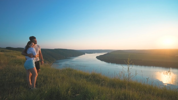 Le couple romantique debout au sommet d'une montagne sur un beau fond de rivière