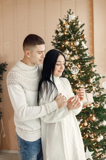 Couple romantique debout près de l'arbre de Noël et étreignant