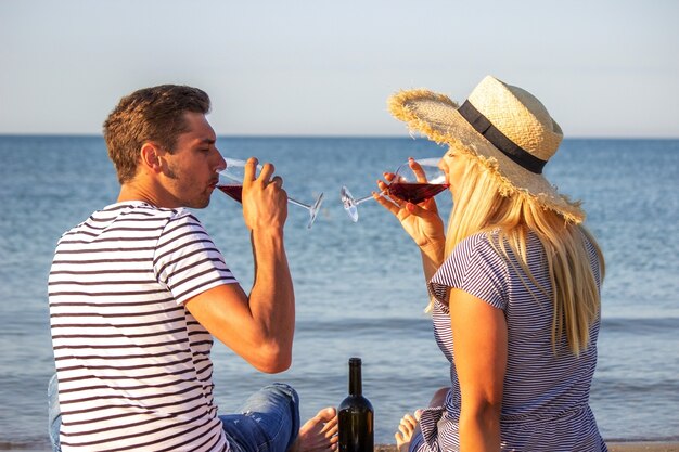 Couple romantique dégustant du vin au bord de la mer