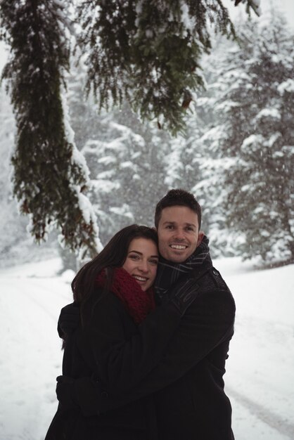 Couple romantique embrassant dans la forêt pendant l'hiver