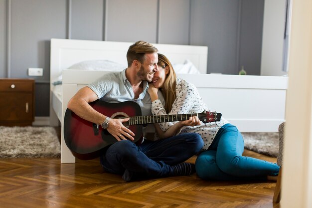 Couple romantique jouant de la guitare au sol