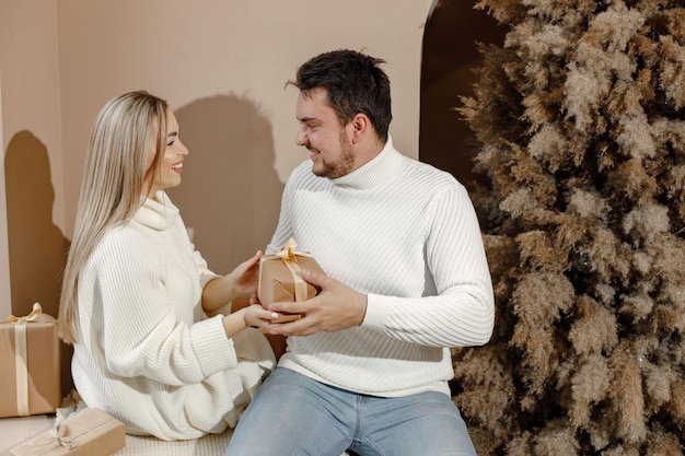 Couple romantique ouvrant un cadeau près de l'arbre de Noël à la maison