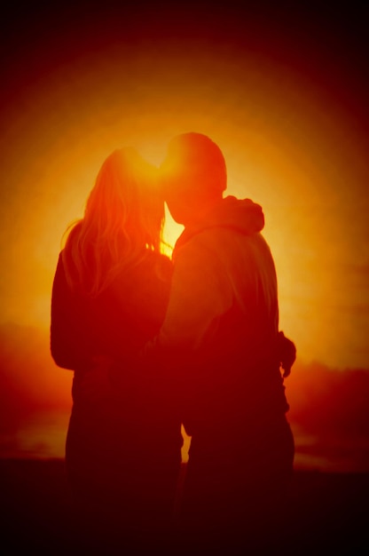 Photo un couple romantique sur la plage contre un ciel orange au coucher du soleil