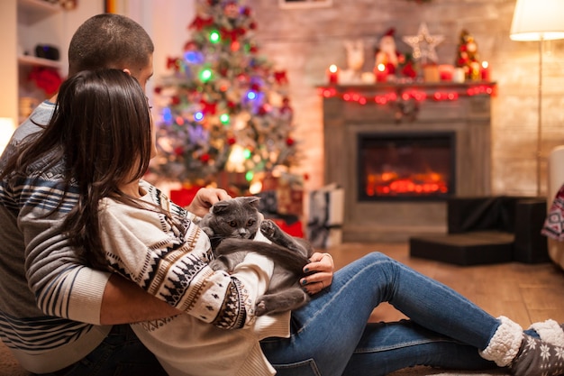 Couple romantique avec pli écossais profitant de Noël devant une cheminée chaleureuse.