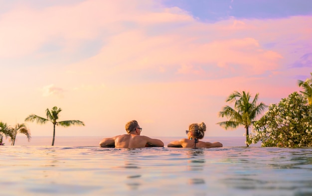 Couple romantique regardant un beau coucher de soleil dans une piscine à débordement de luxe