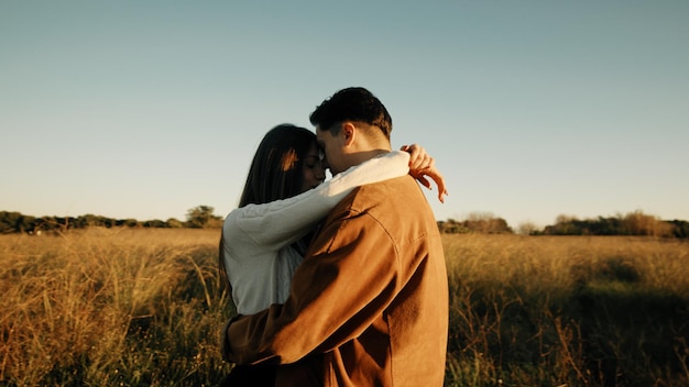 Un couple romantique s'embrassant dans un champ au coucher du soleil