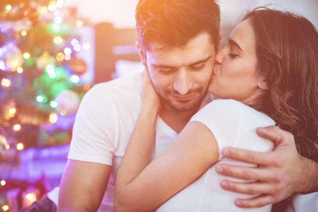 Le couple romantique s'embrassant près de l'arbre de Noël