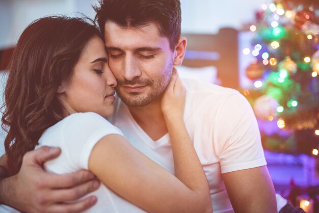 Le couple romantique s'embrasse près de l'arbre de Noël