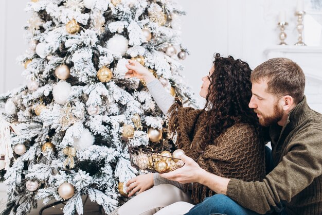 Couple romantique souriant se trouve près de l&#39;arbre de Noël. Concept de Noël et du nouvel an