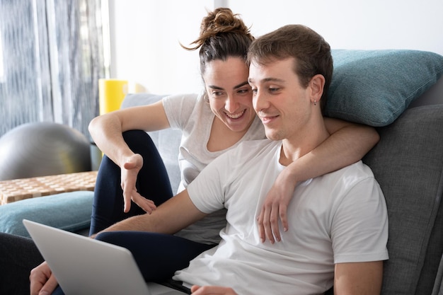 Couple romantique surfant sur le net sur un ordinateur portable assis sur un canapé