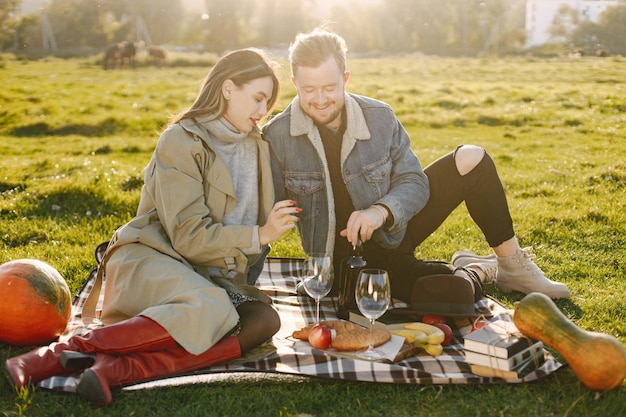 Couple romantique en vêtements de mode assis sur une nature sur un tapis de pique-nique. homme, porter, veste, et, manteau femme