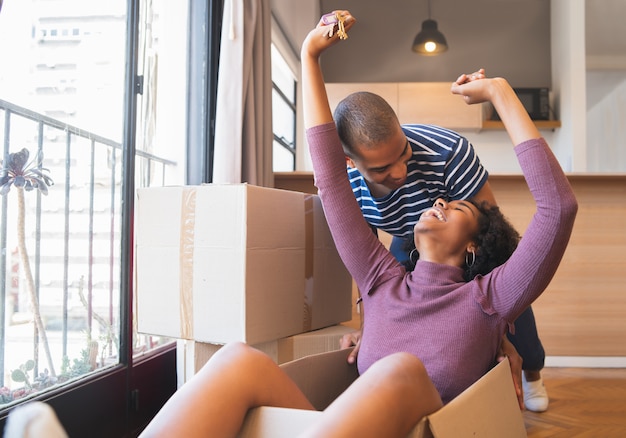 Couple s'amusant avec des boîtes en carton dans la nouvelle maison