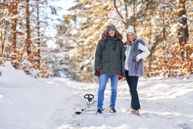 Couple s'amusant avec un traîneau sur la neige dans la neige de l'hiver. photo de haute qualité